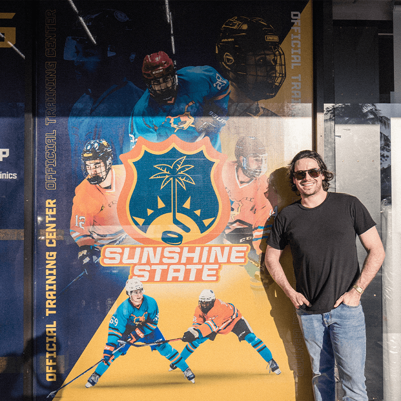 a man poses next to large-scale print of hockey players
