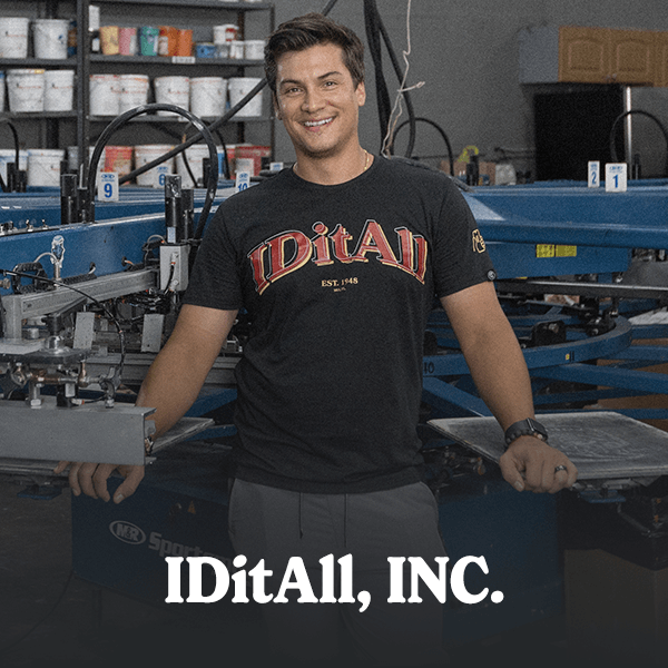 A man smiling at the camera, leaning on screen printing equipment with paint in the background, representing a satisfied customer who has achieved success through Cormorant Marketing's creative marketing services for Jacksonville FL businesses.