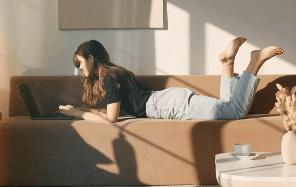 woman on jacksonville fl real estate website a woman scrolls on laptop, laying on couch, observing Jacksonville fl real estate marketing services